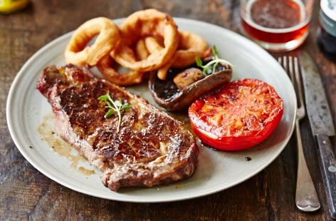 Everyone loves a laid-back British barbecue and this classic steak dish with homemade onion rings and char-grilled tomatoes is the ideal meal to serve