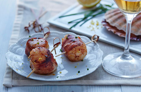 These delicious pan-fried scallop pops make a sophisticated canapé for a dinner party or gathering. The fresh seafood is marinated in zesty lemon and chives and wrapped in salty pancetta before being cooked over a high heat, resulting in wonderfully crisp pancetta and perfectly cooked scallops.