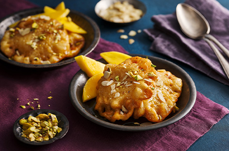 Celebrate Holi with these indulgent malpua. Similar to pancakes, they're coated in sugar syrup and loaded with zingy mango, chopped pistachios and flaked almonds