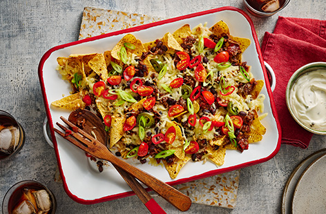 Beef and black beans are cooked with taco seasoning before being piled on top of tortilla chips and baked with cheese