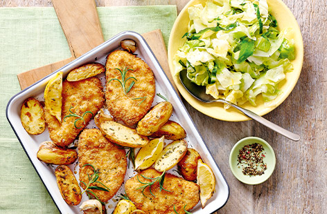 Everyone will enjoy this easy traybake that uses breaded chicken steaks roasted alongside lemony 'n' herby potatoes and served with stir-fried cabbage - winner dinner!