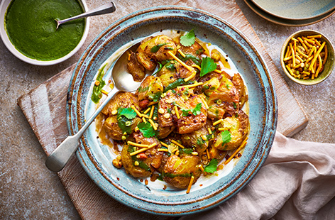 These potatoes are roasted in a blend of spices, then served on mango chutney-spiked yogurt, topped with a coriander drizzle and Bombay mix.