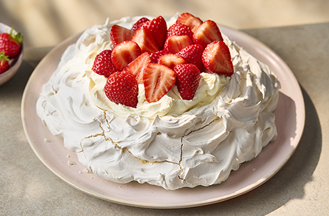 Tuck into this deliciously crisp Pavlova topped with whipped cream and juicy strawberries