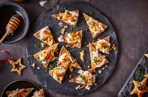 Sourdough is toasted and topped with creamy soft cheese, flame-grilled chicken, walnuts and a drizzle of honey for sweetness in this easy canapé recipe. Perfect for the festive party season!

