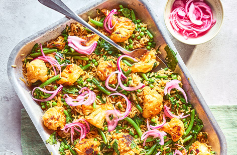 Get your veg in with this vibrant pilaf traybake. Roast your cauliflower with some smoky harissa and stir in the rice and green veg. This tastes great with pickled pink onions on top. 
