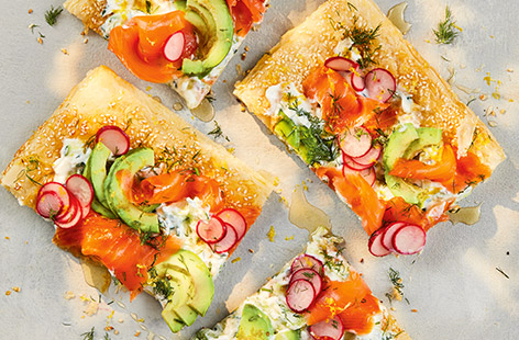 This salmon tart is perfect for a relaxed weekend brunch or light lunch. Puff pastry is topped with tzatziki, pickled radishes, avocado and smoked salmon. And the secret finishing touch? A drizzle of honey to offset the smoky salmon – delicious!