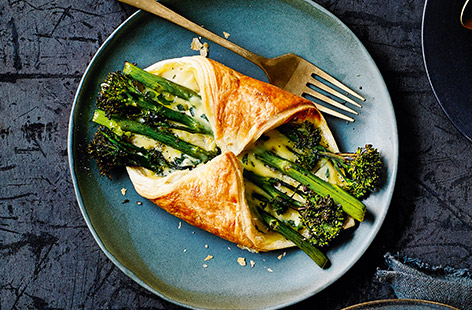Squares of puff pastry with a drizzle of cheese sauce, parsley and broccoli spears placed on the diagonal