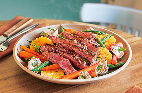 When Sam's housemate Jess gets on the wrong side of a spray tan, Sam knows just what'll cheer her up: a juicy Tesco Finest 30-day matured rib-eye steak, pan-fried to perfection. Sam serves slices of the tender steak with green beans and dollops of soft goat's cheese – not to mention some very appropriate orange and roasted carrots!