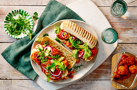 Use leftover fennel spiked pork meatballs and tomato sauce in this spicy sub sandwich recipe. Ciabatta bread is topped with chipotle laced sauce with beans, fresh avocado, meatballs, coriander and plenty of fresh green salad in this midweek dish.