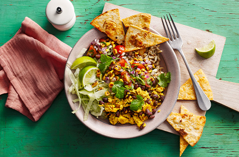 Use leftover scrambled tofu in this colourful Tex-Mex bowl. Wholegrain rice and quinoa are topped with black beans, tofu, crispy tortilla chips, and a fresh corn salsa for a healthy midweek family meal.
