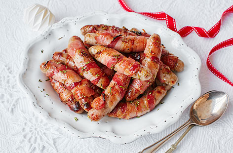 Your Christmas dinner just wouldn't be complete without classic pigs in blankets! This easy Christmas side dish takes Cumberland sausages and blankets them in streaky bacon, coating with a fragrant honey, mustard and rosemary sauce before cooking