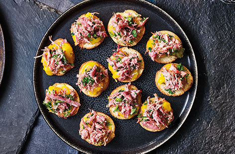 Serve up simple Christmas canapés that layer crostini with mustard piccalilli and zesty, herby ham hock