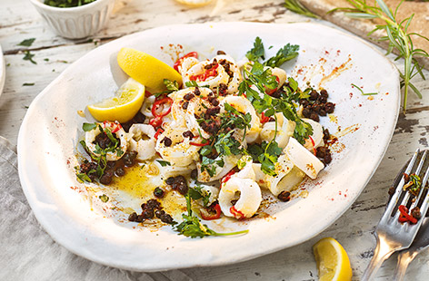 This sticky garlic squid is an ideal easy sharing starter, ready in just 15 minutes. Squid is stir-fried in garlic and chilli until sticky and caramelised, then topped with crispy capers for a simple finishing flourish. Serve with plenty of fresh lemon.