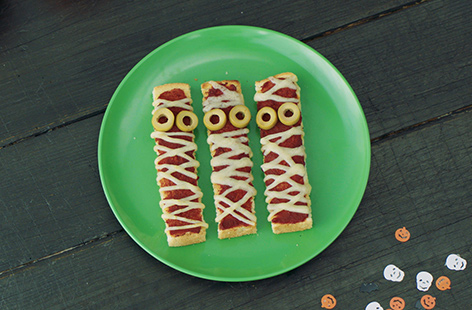 Serve up a spooky snack for Halloween with these fun, gross toasts. Made to look like bandaged mummies, these toast fingers are topped with cheese and tomato for a pizza-like flavour that the kids will love. 