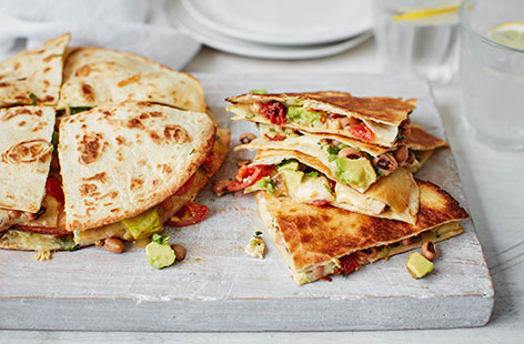 These quesadillas combine mozzarella, mashed avocado and a mix of sun-dried and cherry tomatoes with lime, coriander and black beans for a Mexican taste sensation. This easy, vegetarian recipe makes a great midweek meal.